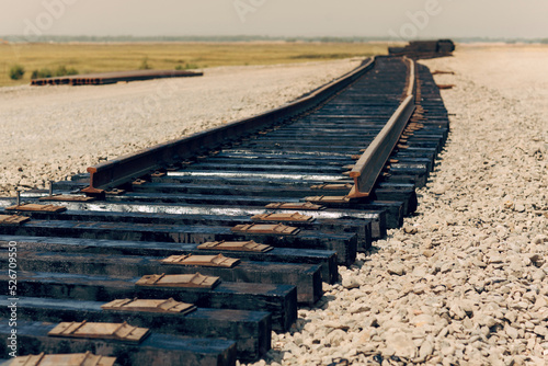 Laying of new railway tracks with wooden sleepers laid on groundwork crushed stone. Railway industry and transport infrastructure.