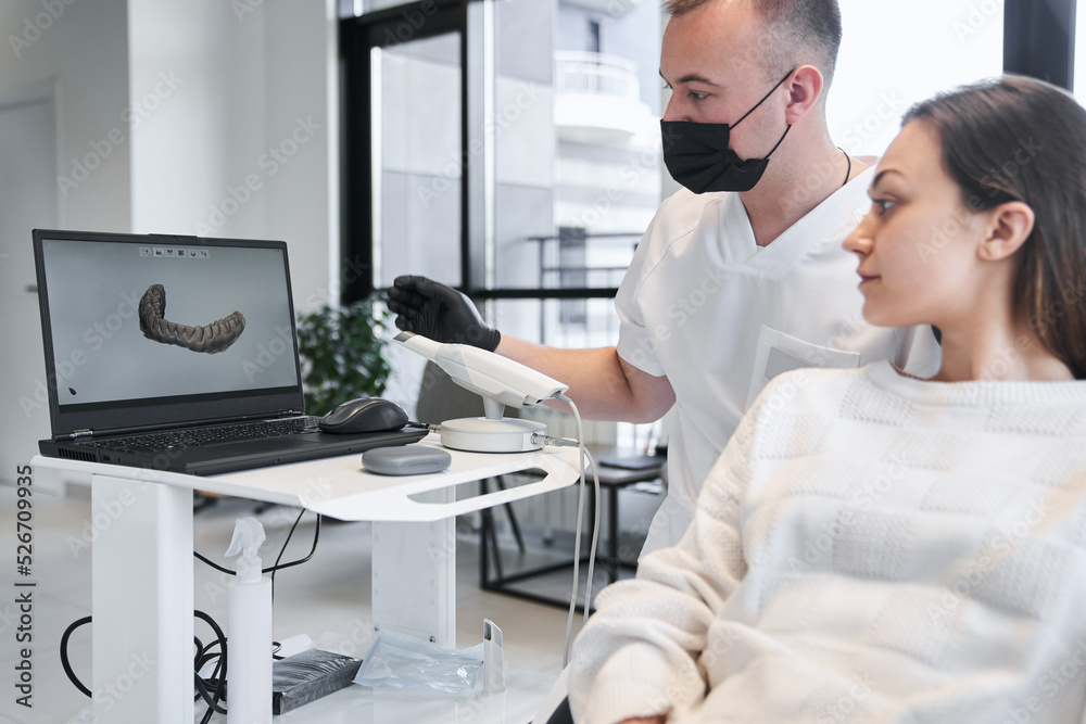 Obraz premium Male doctor and female patient discussing treatment in front of laptop screen