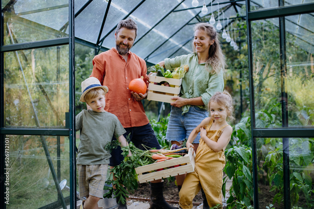 Farmer family with fresh harvest standing in a greenhouse