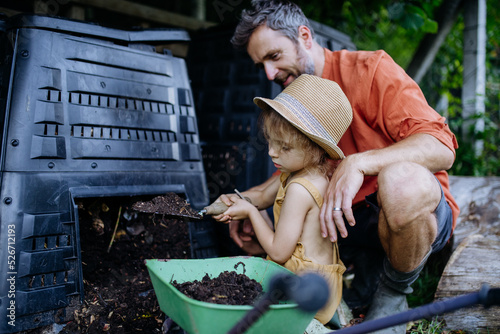 Father with his daughter putting compost out of composter, farmer lifestyle. photo