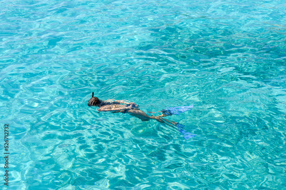 Girl snorkelling as she swims in clear tropical water during a vacation