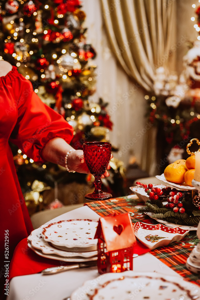 An adult woman in a red dress makes a Christmas serving at home.