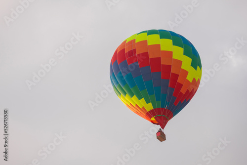 Colorful rainbow hot air balloon flying against grey sky at Winter aerostat festival. Freedom, sport, aircraft concept