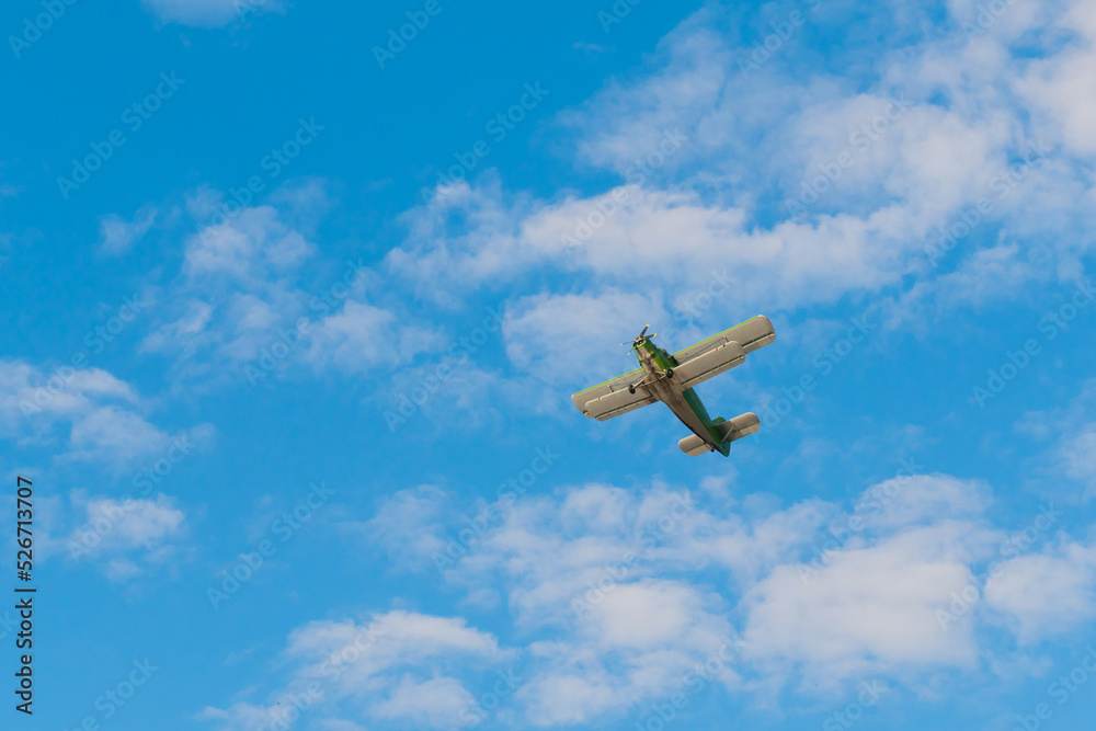 Obraz premium Green biplane, retro airplane flying in blue sky and doing stunts at Air Show. Performance, extreme, aerobatic, sport and aircraft concept