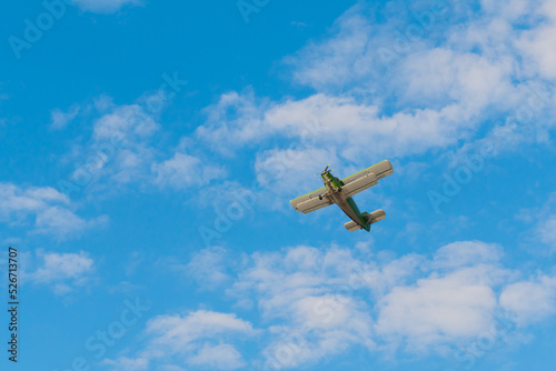 Green biplane, retro airplane flying in blue sky and doing stunts at Air Show. Performance, extreme, aerobatic, sport and aircraft concept