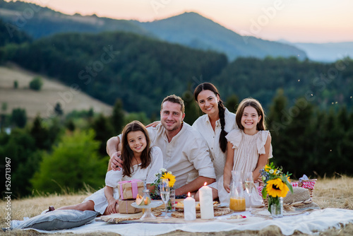 Portrait of happy family with children having picnic in nature in summer.