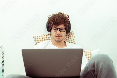 Young Caucasian Man work from home on laptop and connect online to office indoor for remote internet workplace. Young Adult male is freelance work smart on notebook sitting on Bed bedroom, copy space