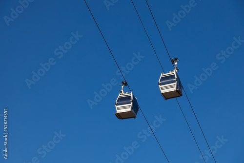 A pair of sky lift cabins in front of a clear blue sky. Tbilisi, Georgia.