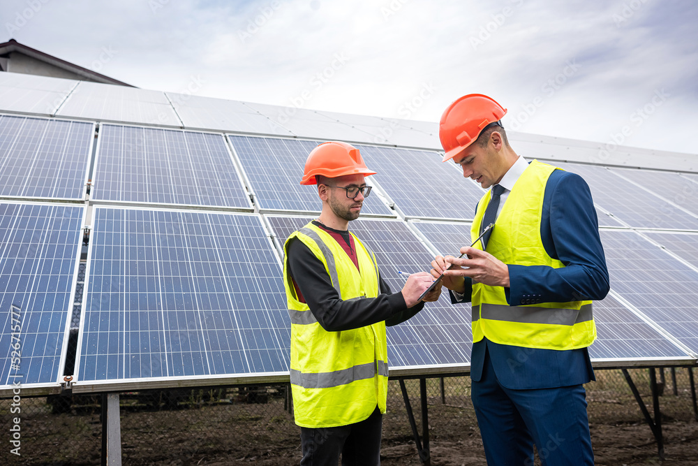 young workers in helmets of working jackets discuss the plan of work  solar panels for economy