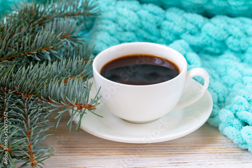 A cup of coffee, a plaid, and a Christmas tree branch
