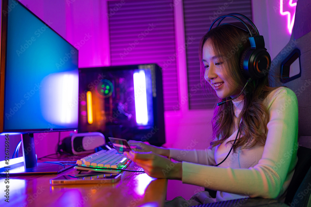 Top up online game with credit card concept. Gamer and E-Sport online of Asian woman playing online computer video game with lighting effect, broadcast streaming live at home. Gamer and E-Sport gaming Top up online game with credit card concept. Gamer and E-Sport online of Asian woman playing online computer video game with lighting effect, broadcast streaming live at home. Gamer and E-Sport gaming