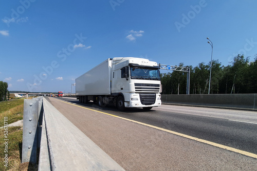A white truck is moving along the autobahn. Freight, container transportation.