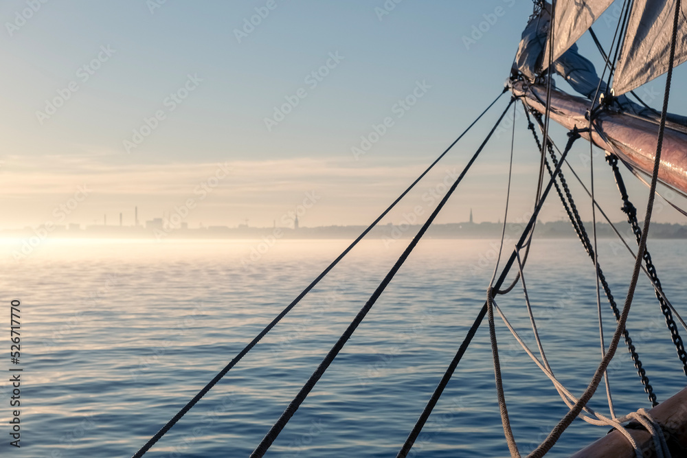 Sail boat at sunset, city on the horizon