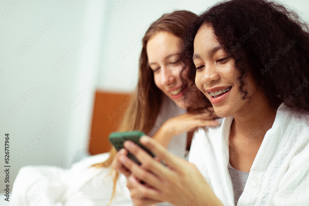 Caucasian and black women love together and hug hold as diversity person. Young Adult Romantic couple look at smart phone photo chat text as feeling happy smile togetherness and diversity, copy space Caucasian and black women love together and hug hold as diversity person. Young Adult Romantic couple look at smart phone photo chat text as feeling happy smile togetherness and diversity, copy space