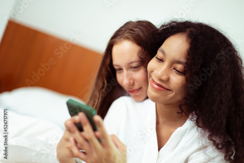 Caucasian and black women love together and hug hold as diversity person. Young Adult Romantic couple look at smart phone photo chat text as feeling happy smile togetherness and diversity, copy space