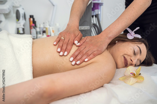female therapist doing massaging on a female patient back, in the spa