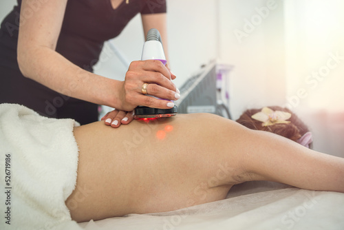 masseur doing anti-cellulite massage with vacuum massage device female client in spa clinic