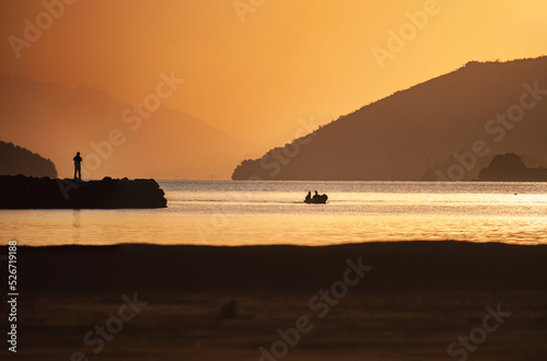 Vista para a baia de Paraty ao nascer do sol, silhoueta de pescadores e passaros com o amanhecer dourado photo
