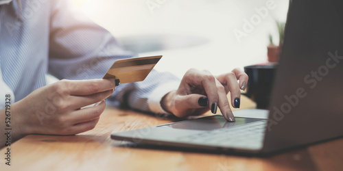 Hands holding credit card, typing on the keyboard of laptop, onine shopping detail close up photo