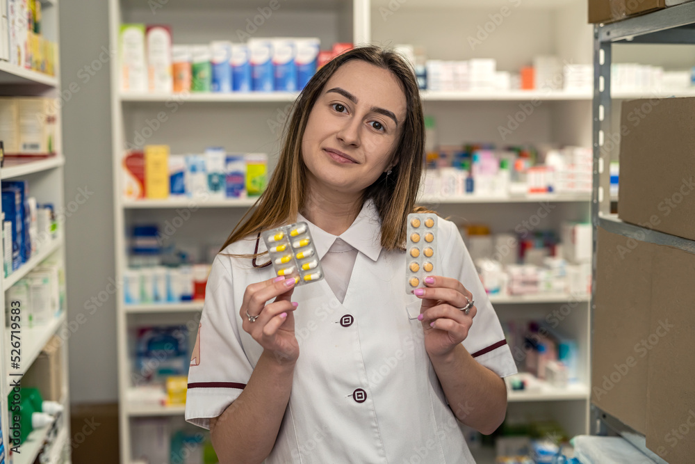 pharmacist woman holds many medicines in her hands and arranges them on the shelves.