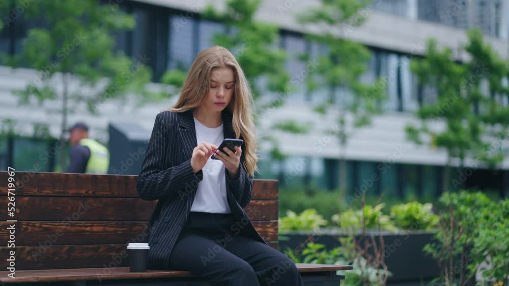beautiful young woman is sitting on bench city center and reading news in social media by smartphone beautiful young woman is sitting on bench city center and reading news in social media by smartphone