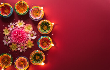 Happy Diwali - Clay Diya lamps lit during Diwali, Hindu festival of lights celebration. Colorful traditional oil lamp diya on red background