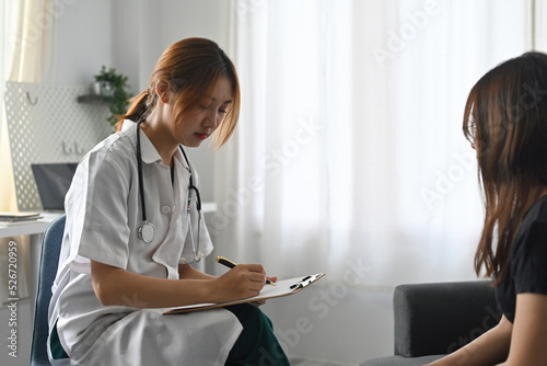 Asian female doctor consults patient and filling documant form. photo
