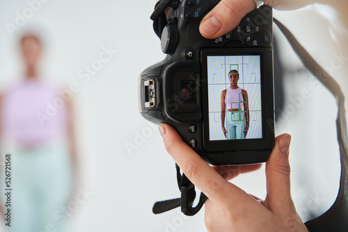 Multiracial girl standing in front of the camera. Her photo at the camera screen