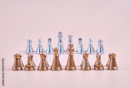 Golden chess before silver chess on a beige background.