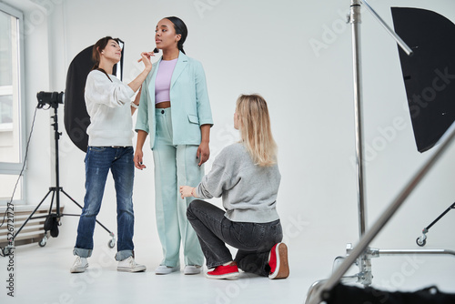 Woman looking away while professional team f make up artist and stylist working on her look photo