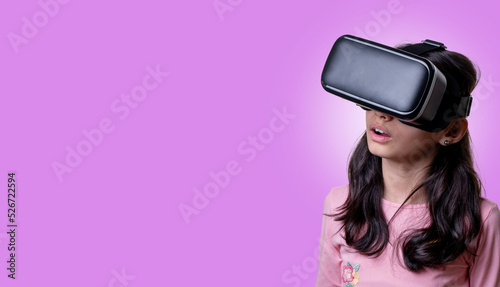 VR glasses   little girl with virtual reality headset. Innovation technology and education concept. Funny girl using a virtual reality headset isolated on pink background