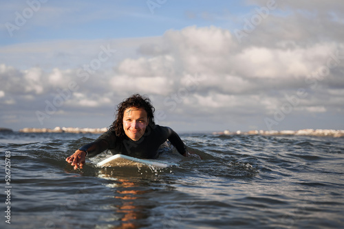 Caucasian positive woman laying at the board and riding waves © Yakobchuk Olena