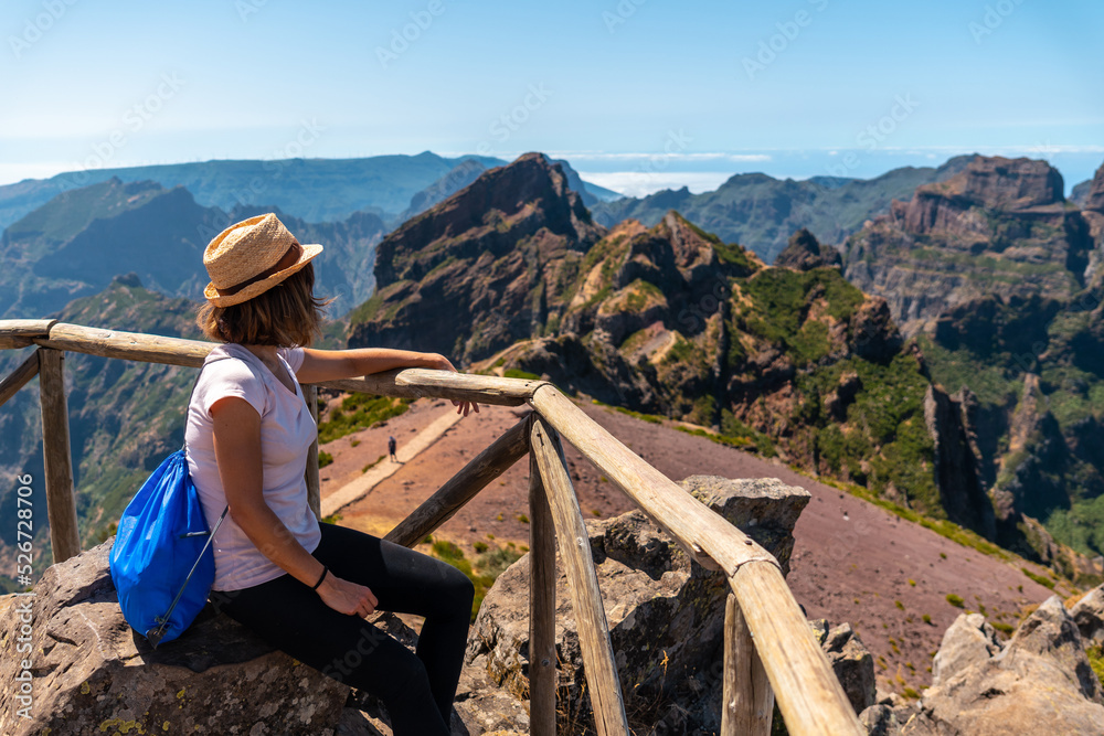 Naklejka premium A tourist sitting looking at the mountains in the mountains at Pico do Arieiro, Madeira. Portugal