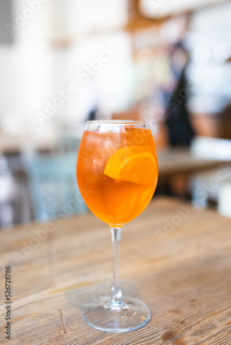 Glass of ice cold Aperol spritz cocktail served in a wine glass, decorated with slices of orange. Summer fresh cocktail in restaurant. Concept of italian cuisine.