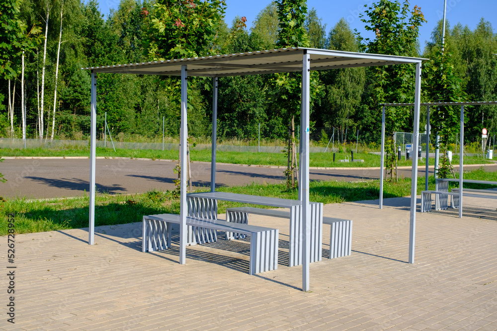 Rest area for motor travelers Poland. A bench with a table with a roof. Expressway stop. Large Parking with light but without cars on the track on a summer.