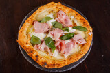 Pizza gourmet napoletana con provola, prosciutto cotto, stracciata di bufala e basilico fresco servita in una pizzeria
