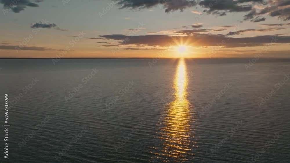 Tropical golden sunset over ocean water slow motion aerial view. Sun setting reflection on seascape. No-people sand beach at sea bay. Calm waterscape at sunny evening. Summer vacation.