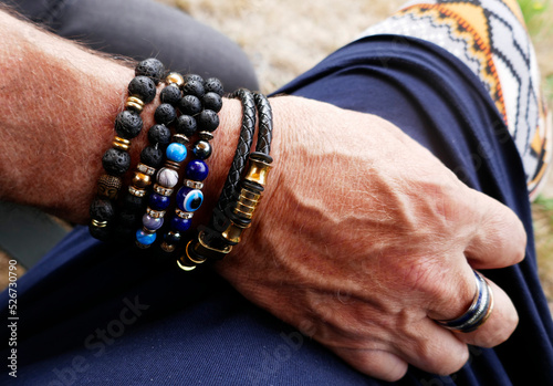 Senior man lies his arm on the leg of his wife. He likes wearing lava stone and other breaded bracelets photo