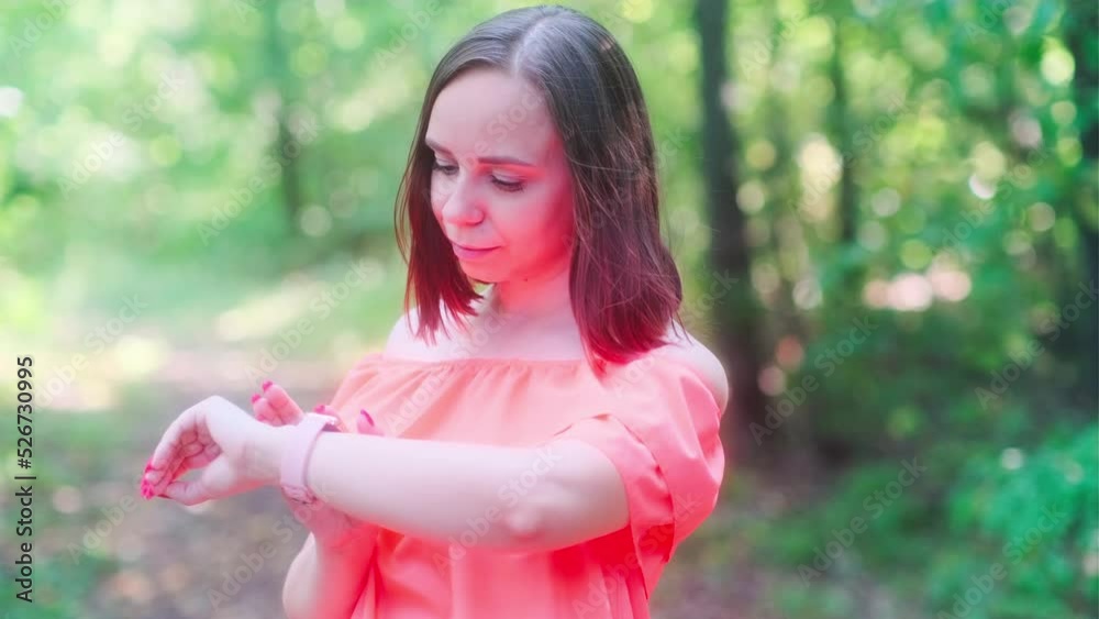 Woman using smart watch in park. Female checking notifications on smart watch on summer day in park Woman using smart watch in park. Female checking notifications on smart watch on summer day in park