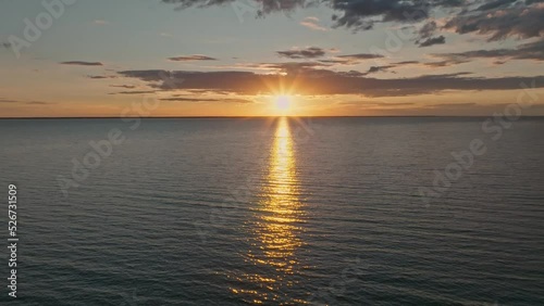 Tropical golden sunset over ocean water slow motion aerial view. Sun setting reflection on seascape. No-people sand beach at sea bay. Calm waterscape at sunny evening. Summer vacation.