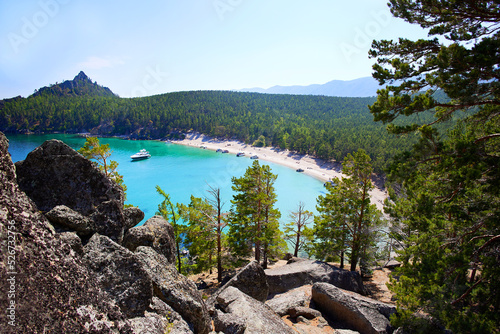 Lake Baikal, Babushka Bay in summer. Yachts in a bay with turquoise water color. Around the rocks, huge stones and coniferous forest.