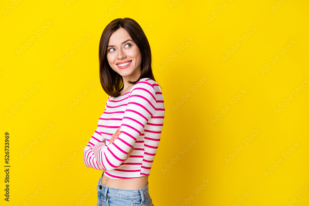 Photo portrait of cheery confident young girl look empty space crossed arms wear trendy striped garment isolated on yellow color background Photo portrait of cheery confident young girl look empty space crossed arms wear trendy striped garment isolated on yellow color background