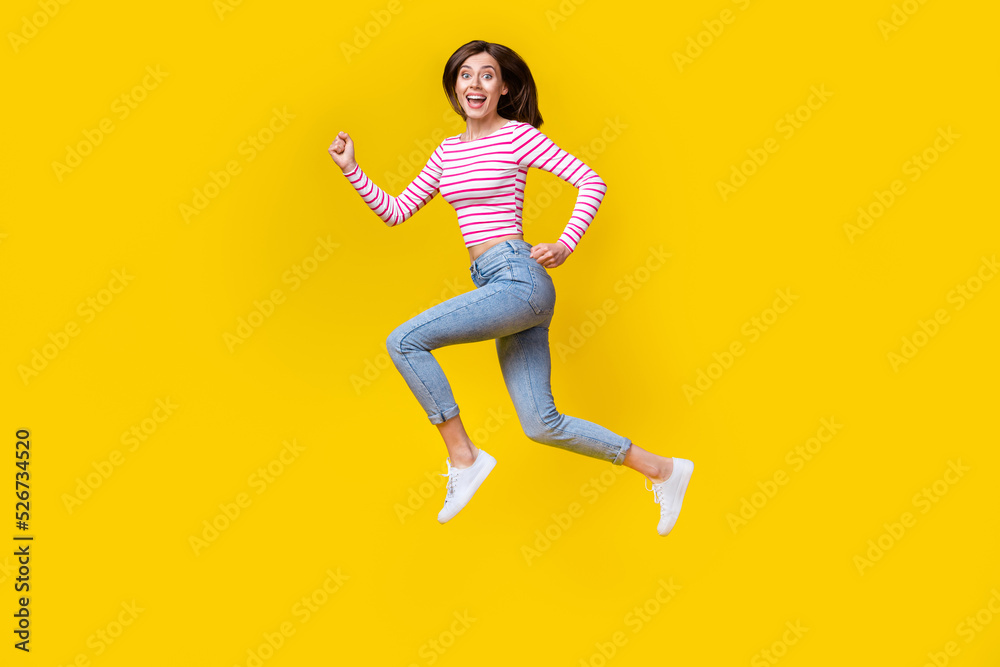 Full body photo of gorgeous young lady excited running fast hurry sales dressed trendy striped outfit isolated on yellow color background