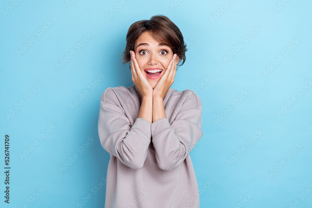 Photo of positive impressed lady toothy smile arm touch cheekbones face dont believe rejoice win isolated on blue color background Photo of positive impressed lady toothy smile arm touch cheekbones face dont believe rejoice win isolated on blue color background