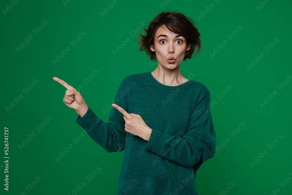 Young woman expressing surprise while pointing fingers aside Young woman expressing surprise while pointing fingers aside