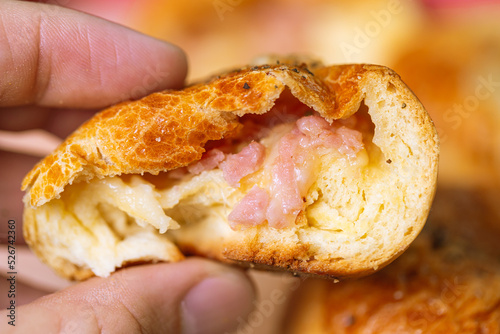 Pão pizza. Um homem segurando um salgado brasileiro, pão pizza, de massa assada recheado com presunto e queijo muçarela com orégano em cima. Comida, Comida brasileira., Lanche, Salgado,  photo