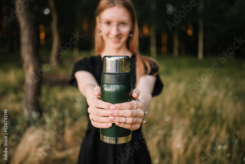 beautiful young girl with thermos is resting in nature