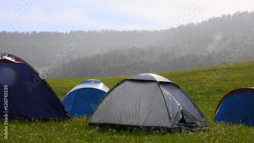 Torrential summer rain caught the tent city of tourists while traveling. During the hike, travelers take shelter from the rain in waterproof tents