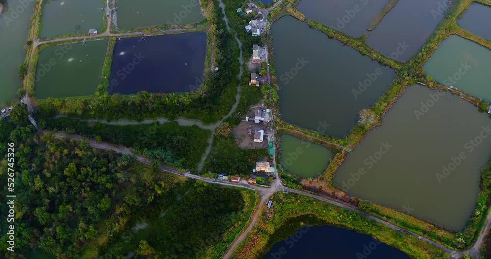 Top view drone shot of a wetland area during the end of the day above some road and a village.
