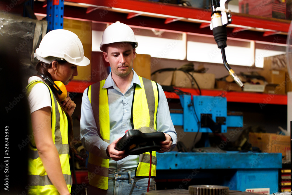 Two maintenance engineers men and women inspect relay protection system with laptop comp. They work a heavy industry manufacturing factory. Two maintenance engineers men and women inspect relay protection system with laptop comp. They work a heavy industry manufacturing factory.